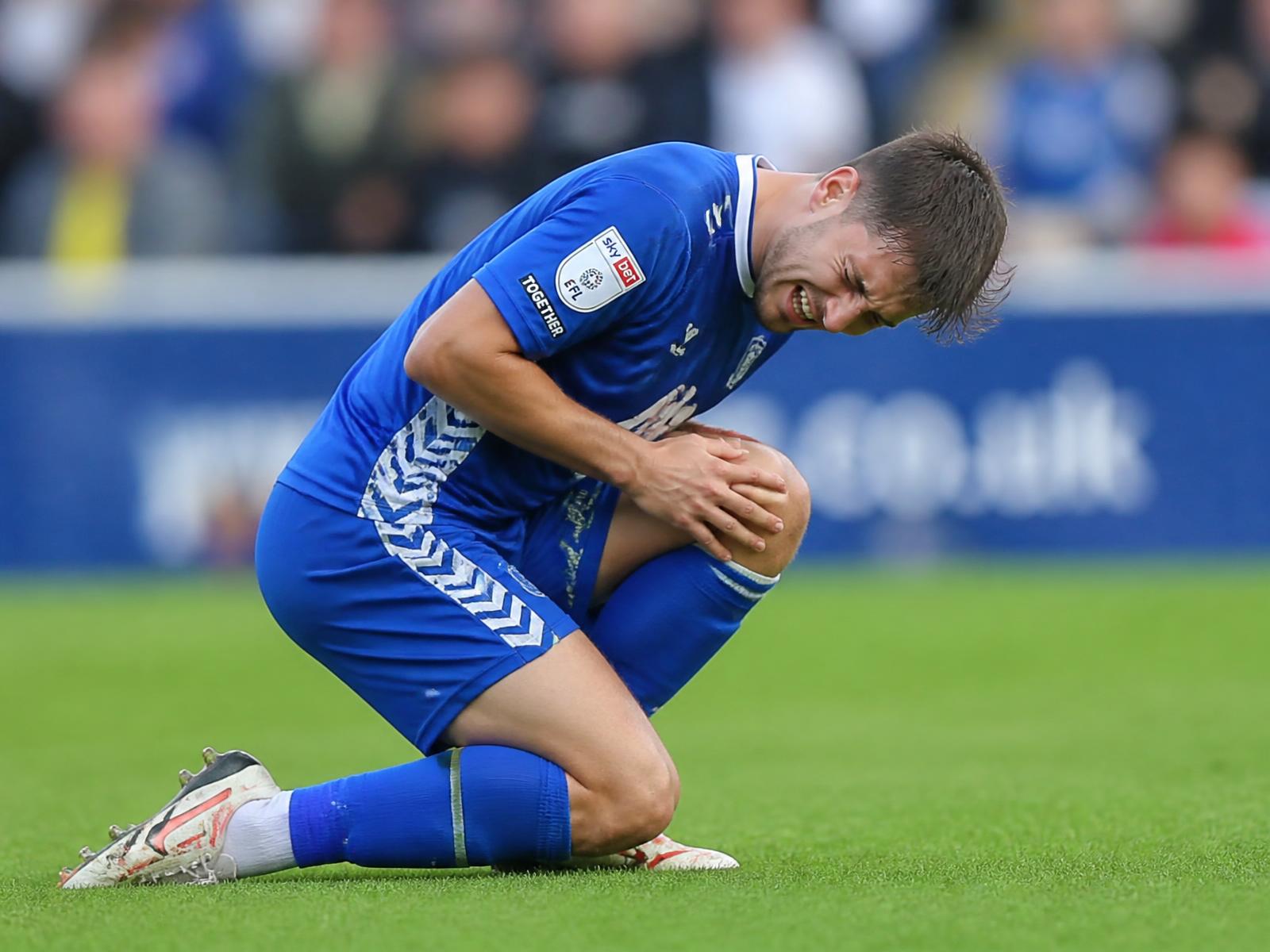 Footballer kneeling on the pitch holding an injured knee